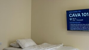 A hotel room with a bed, a wall-mounted sign with house rules, and a Wi-Fi symbol. - Abdali elite studio (Amman)