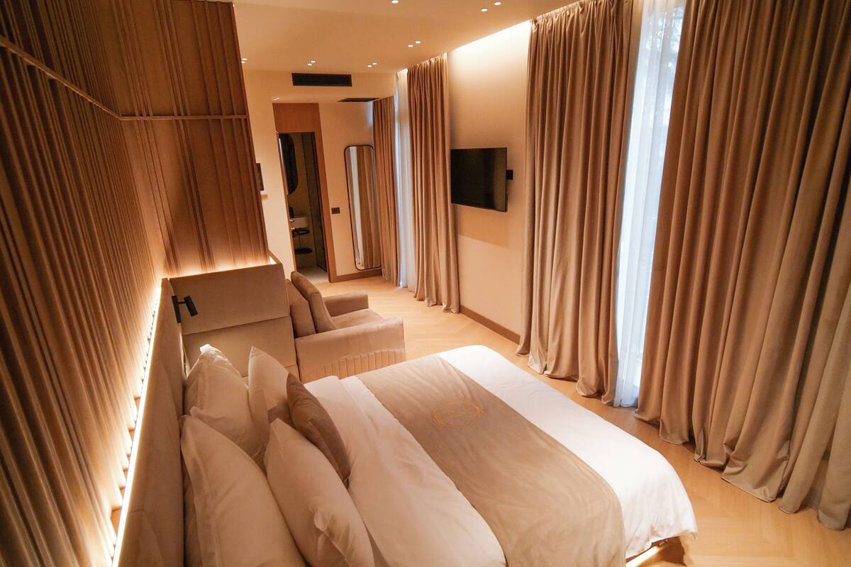 A modern hotel room with a large bed, a sofa, and a TV.
