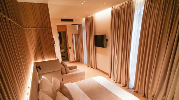 A modern hotel room with a large bed, a seating area, and a television. - Post Inn  (Tirana)