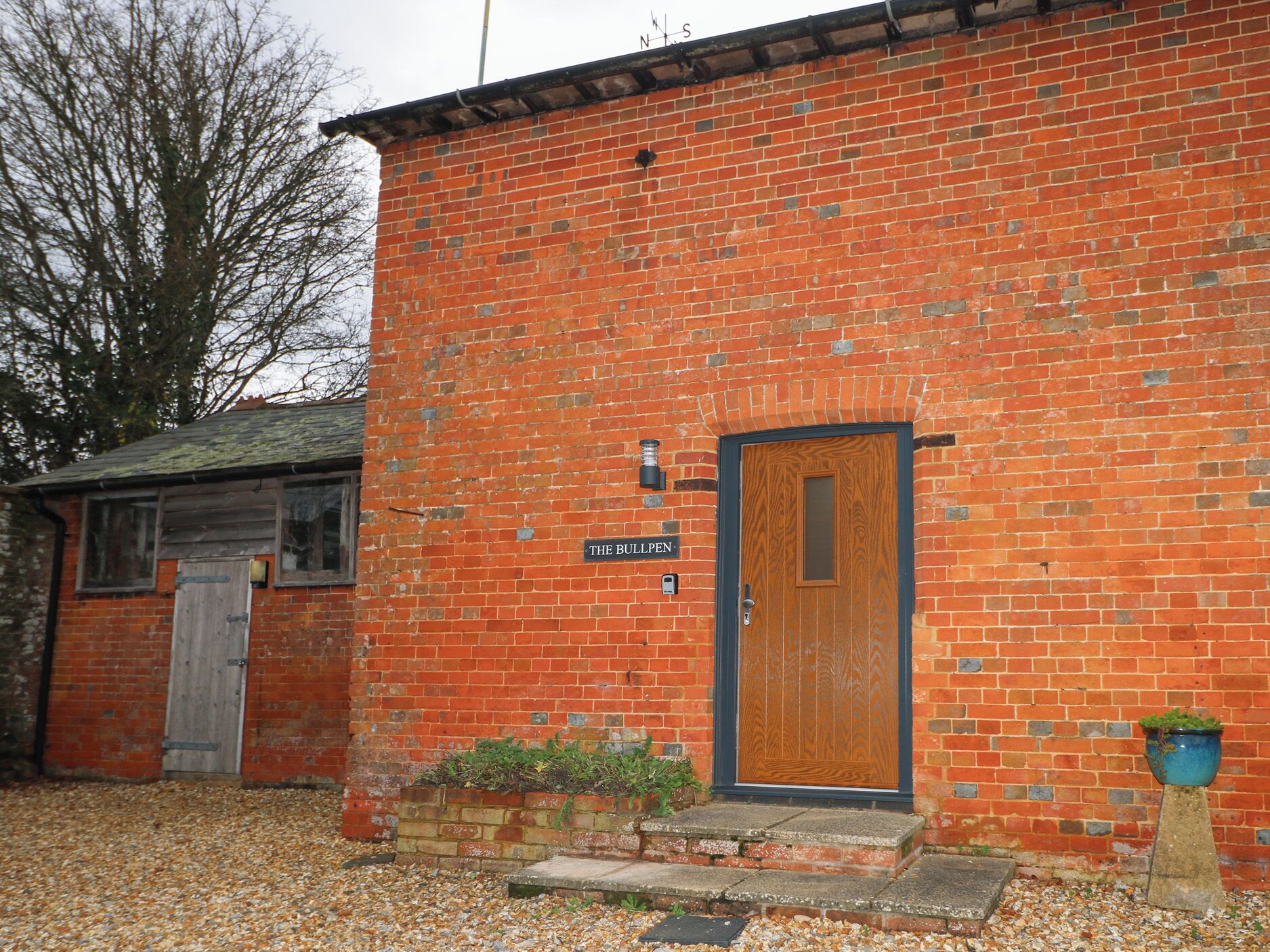 A brick building with a wooden door labeled "THE BULLPEN."