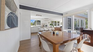 Eine moderne Küche mit weißen Schränken, einem Holztisch und einem großen Fenster.