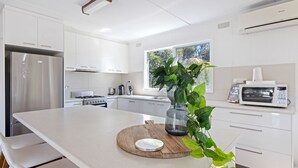 Eine moderne Küche mit weißen Schränken, Edelstahlgeräten und einem großen Fenster für natürliches Licht.