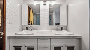 Ein modernes Badezimmer mit zwei Waschbecken, einem großen Spiegel und einem Waschtisch mit Schubladen.