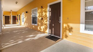 A yellow building with a covered walkway, doors, and windows.