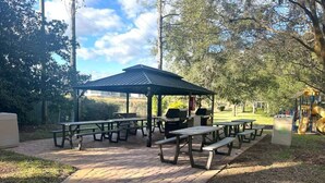 A picnic area with multiple tables and benches, a covered pavilion, and a grill.