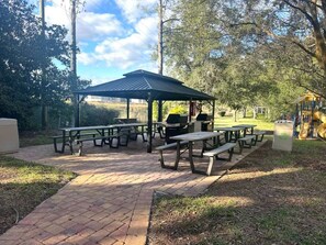 A picnic area with multiple tables and benches, a covered pavilion, and a grill.