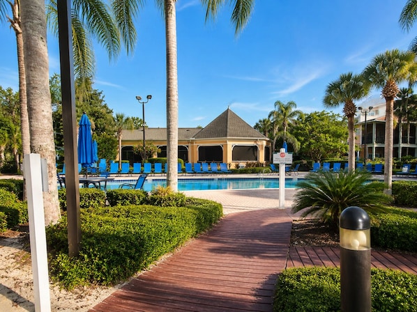 A pool area with blue lounge chairs, a gazebo, and a pathway leading to the pool.