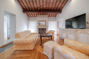 Ein Wohnzimmer mit Kamin, Sofas, Fernseher und Schrank.