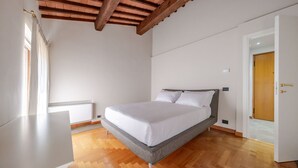 A bedroom with a bed, wooden floor, white walls, and a wooden ceiling. - ApartmentsArena - Capitolium Verona 6 (Verona)