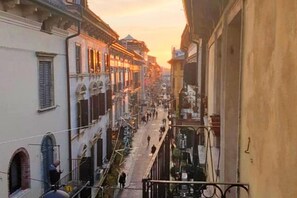 A narrow street with buildings on either side, a pedestrian walkway, and a bridge in the distance. - ApartmentsArena - Capitolium Verona 6 (Verona)