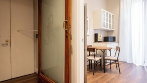 A room with a wooden door, a glass partition, a dining area with a table and chairs, and a kitchen with cabinets and a microwave. - Casa Eva - Four Bedroom Apartment, Sleeps 10 (Naples)