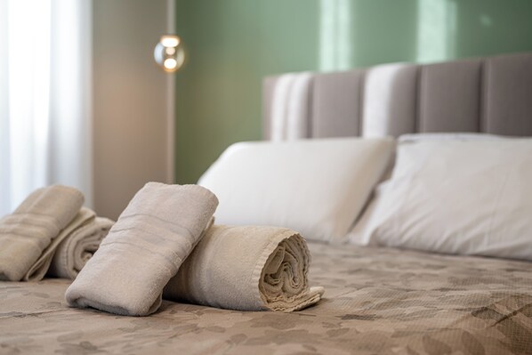 A neatly made bed with rolled towels and a headboard. - Casa Eva - Four Bedroom Apartment, Sleeps 10 (Naples)