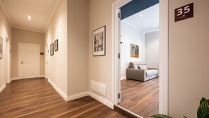 A hallway with wooden flooring, framed pictures on the walls, and a door labeled '18'. - Casa Eva - Four Bedroom Apartment, Sleeps 10 (Naples)