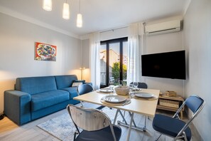 Un salon moderne avec un canapé bleu, une table à manger et un téléviseur fixé au mur.