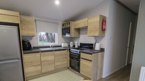 Eine kleine Küche mit Holdekor, einem Backofen, einem Gaskochfeld und einem Kühlschrank.