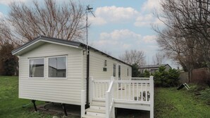 Ein eingeschossiges Mobilheim mit Veranda und kleiner Terrasse.