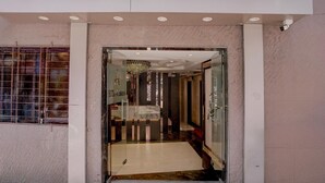 Ein Hotel Eingang mit Glastür, einer Kristallleuchter und einem Marmorboden.