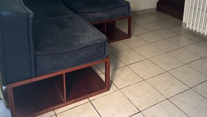 Ein dunkelgraues Sofa in einem Raum mit Fliesenboden und einem weißen Heizkörper.