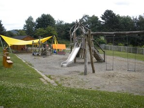 A playground with a slide, swings, and a wooden climbing structure. - Himmelberg Holiday home (66) - Holiday home Meiß Öfingen (Bad Dürrheim)