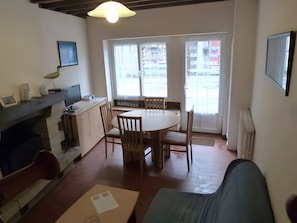 Un coin repas avec une table ronde et des chaises, un espace cuisine équipé d’une cuisinière, et une fenêtre donnant sur l’extérieur.