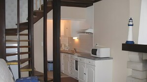 Een knus woongedeelte met een kitchenette, een trap en een bed.