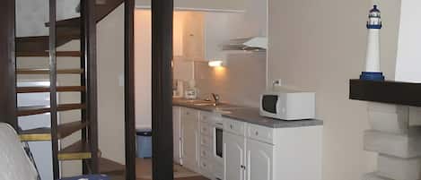A compact living space with a kitchenette, a staircase, and a bed.