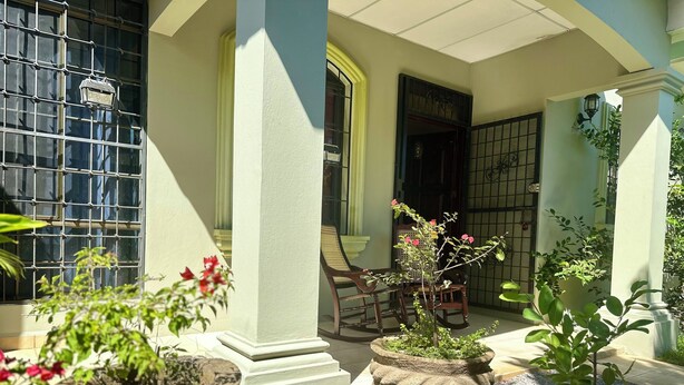 A courtyard with a seating area, potted plants, and a window with a metal grid. - Beautiful bedroom shared house in charming León awaits you (León)
