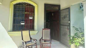 A room with a large window, a door with a metal gate, and two chairs. - Beautiful bedroom shared house in charming León awaits you (León)