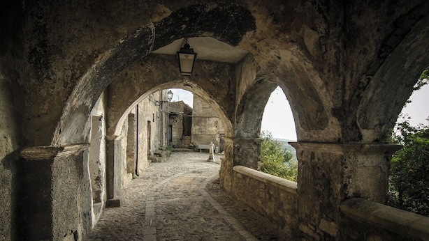An arched stone corridor with a cobblestone floor, leading to a distant view. - Locanda Il Tempo (Cleto)