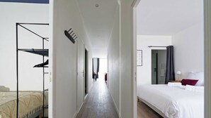 A hotel room with a bed, a desk, and a chair. There is a hallway leading to another room. - Villa Napoléon - Au coeur d'Autun (Autun)