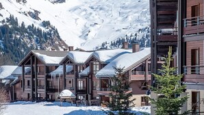 A snow-covered mountain with a wooden lodge featuring multiple balconies and a ski lift in the background. - Cozy 2-bedroom apartment in charming Flaine with swimming pool- ski in&out (Arâches-la-Frasse)