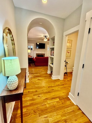 A hallway with wooden flooring, a red sofa, and a lamp on a table. - Charming Walkable Downtown Southern Pines 3 bed/2-1/2 Bath! (Southern Pines)