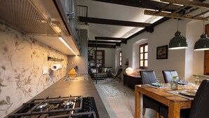 A modern kitchen with a gas stove, wooden dining table, and chairs. There is a staircase leading to an upper level. - Spacious listed vacation apartment between Lake Como & Chiavenna (Lombardia)
