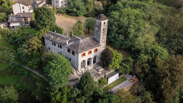 An aerial view of a historic building with a tower, surrounded by dense greenery. - Spacious listed vacation apartment between Lake Como & Chiavenna (Lombardia)