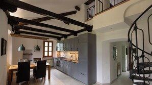 A modern kitchen with grey cabinets, a wooden dining table, and a staircase with a black railing. - Spacious listed vacation apartment between Lake Como & Chiavenna (Lombardia)