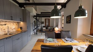 A modern kitchen with grey cabinets, a wooden dining table set with plates and glasses, and a staircase leading to an upper level. - Spacious listed vacation apartment between Lake Como & Chiavenna (Lombardia)
