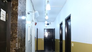 Un pasillo con suelo de mármol, puertas blancas y negras, y lámparas colgantes.