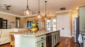 A kitchen with a central island, stainless steel appliances, and hanging pendant lights. - Coral Oasis: Screened Lanai with Private Heated Pool & Spacious 4-Bed Retreat (Cape Coral)