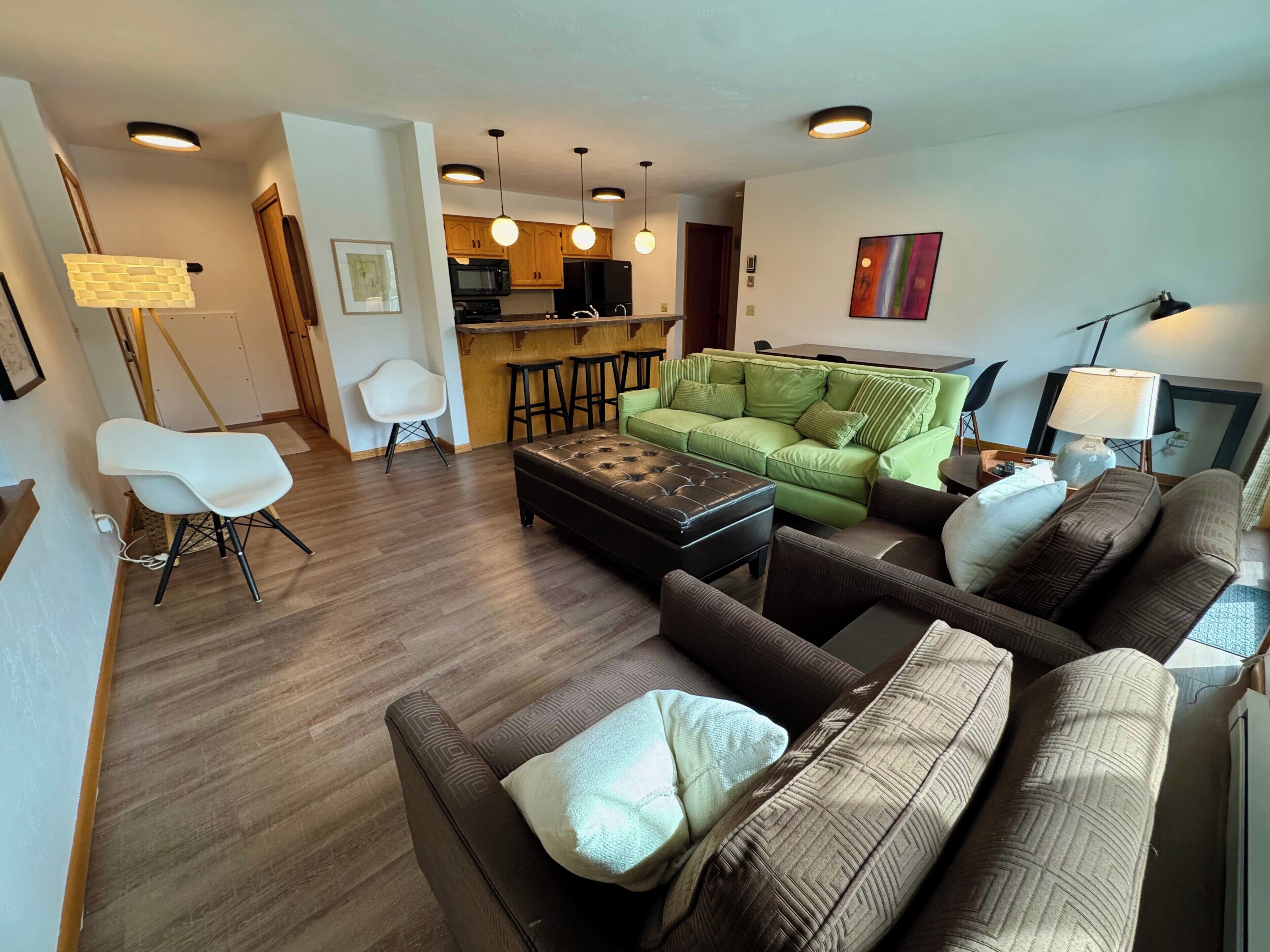 Un salon comprenant un canapé, un pouf et un coin repas avec un bar.