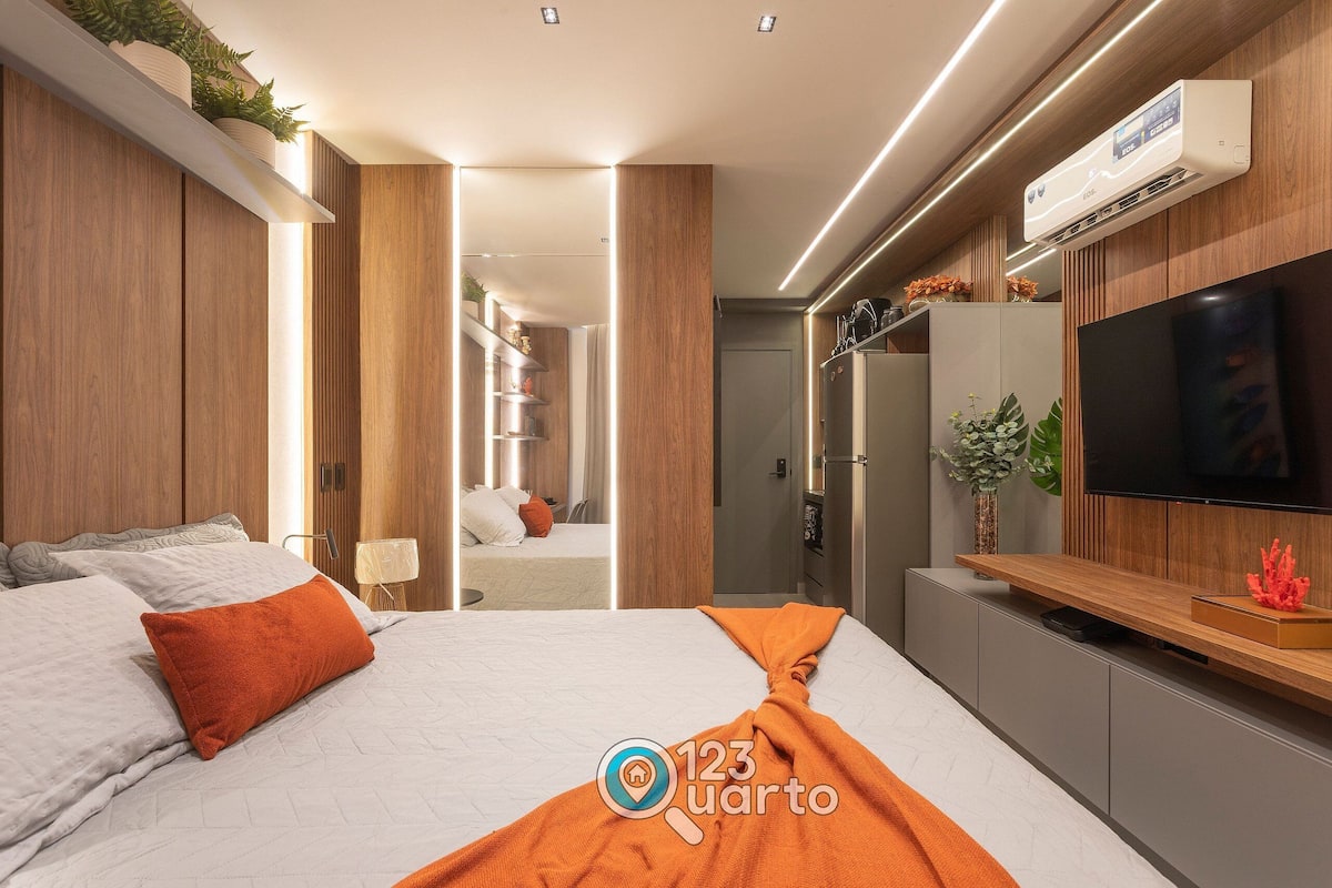 A modern hotel room with a bed, TV, and built-in air conditioning unit.