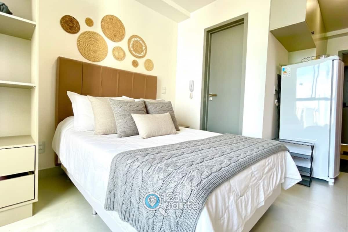 A bedroom with a bed, a wardrobe, a door, and a refrigerator.