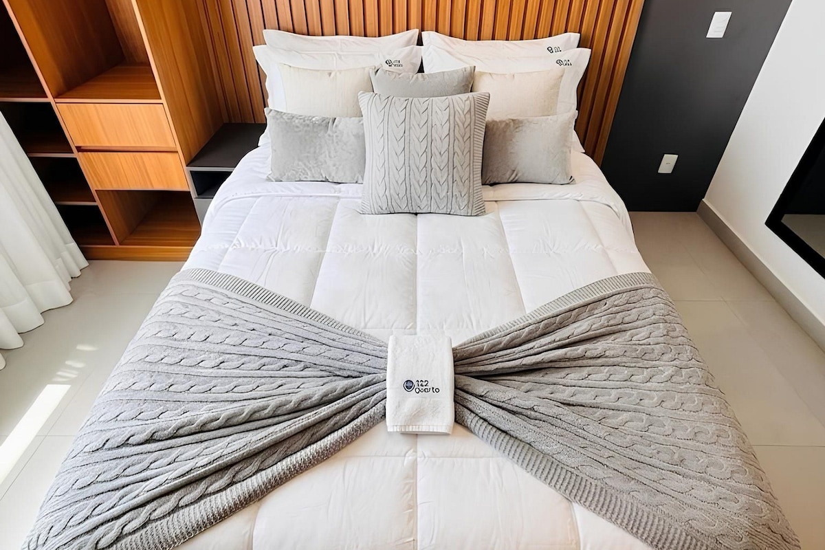 A modern bedroom with a bed, wooden shelving, and a headboard.