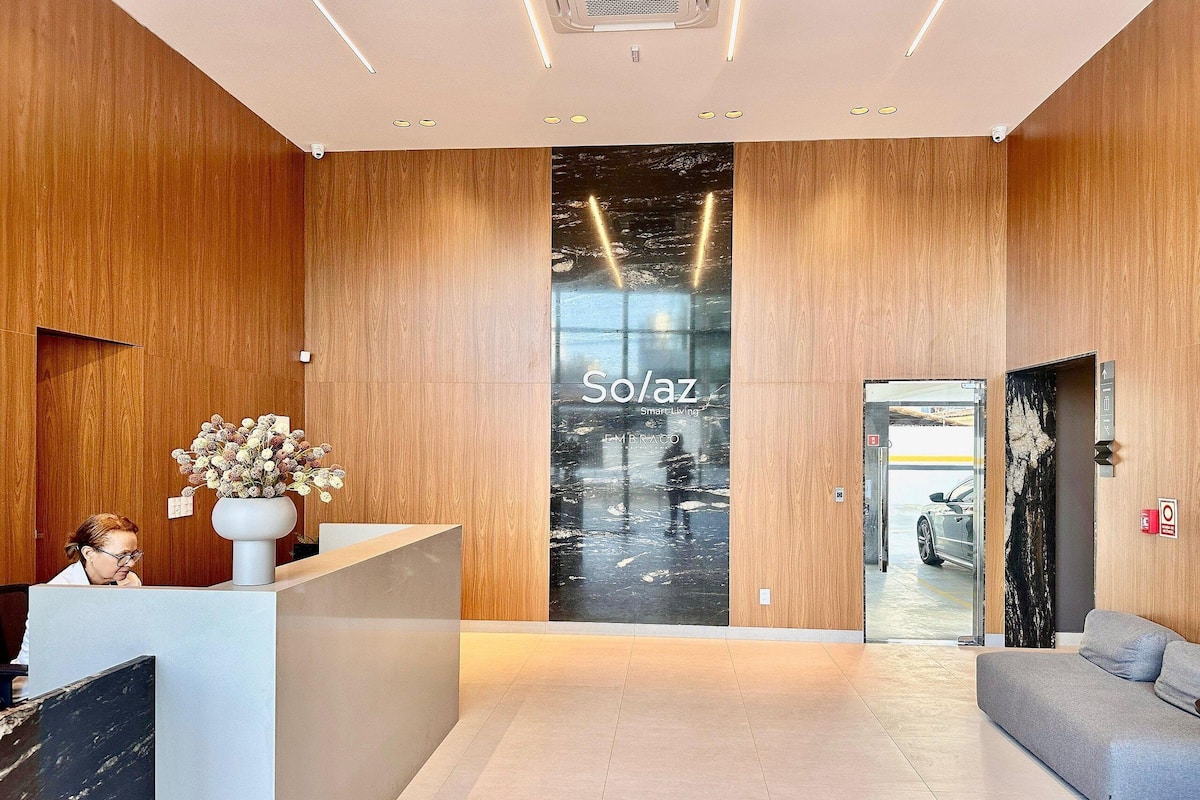 A modern reception area with a wooden finish, a reception desk, a large glass window, and a sofa.
