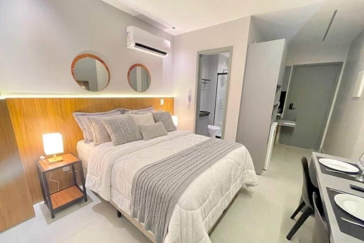 A modern bedroom with a bed, bedside table, and a mirror.