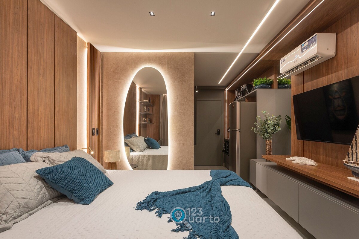A modern bedroom with a bed, TV, and built-in wardrobe.