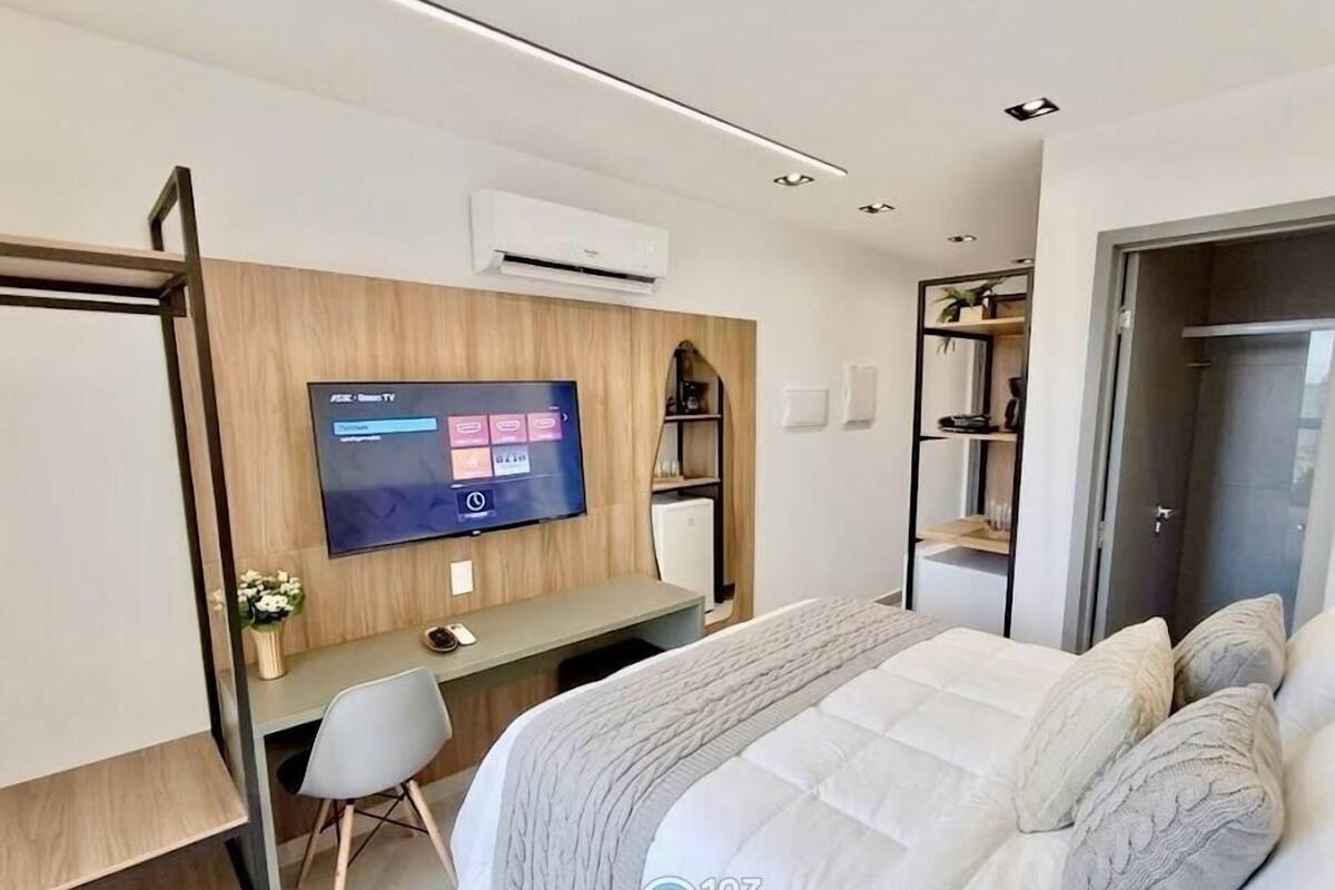 A modern hotel room with a bed, a desk, a TV, and a wardrobe.