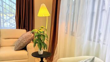 Una sala de estar con un sofá color beige, una mesa redonda con una planta y un sillón blanco.