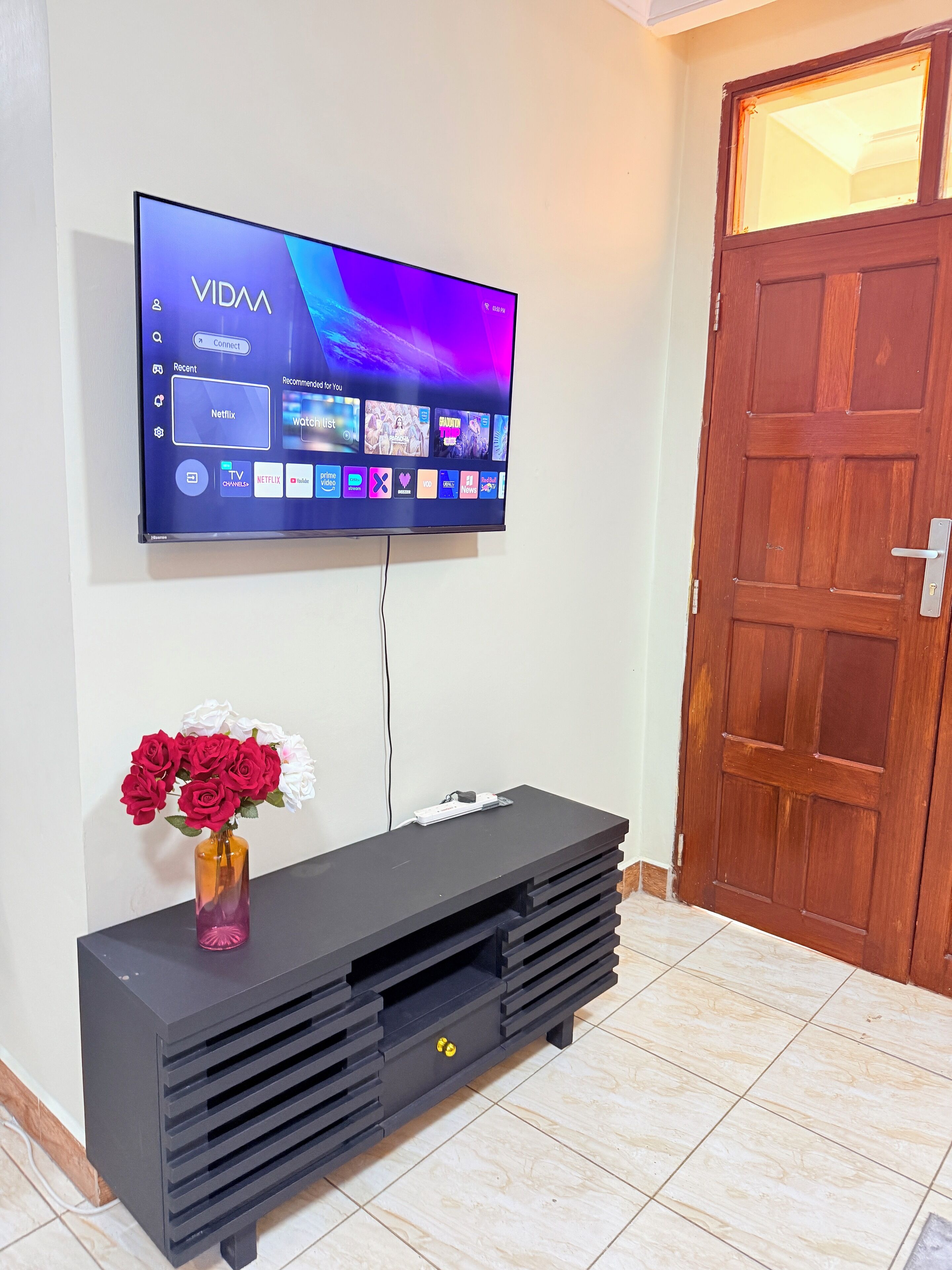 Televisor de pantalla plana montado en la pared, mostrando diferentes servicios de transmisión.