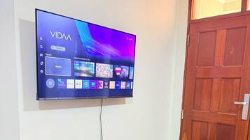 Televisor de pantalla plana montado en la pared, mostrando diferentes servicios de transmisión.