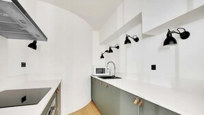 Een moderne keuken met witte aanrechtbladen, een ingebouwde magnetron en een roestvrijstalen afzuigkap.